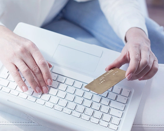 Kéz bankkártyát tart és laptopon gépel. Hitelek és finanszírozás vállalkozásoknak.